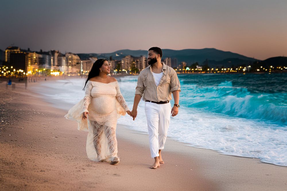 A couple walking hand in hand on a beach at sunset with city lights twinkling in the background.