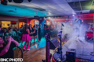 Audience dancing and enjoying a live band performance at a packed indoor music venue in San Antonio.
