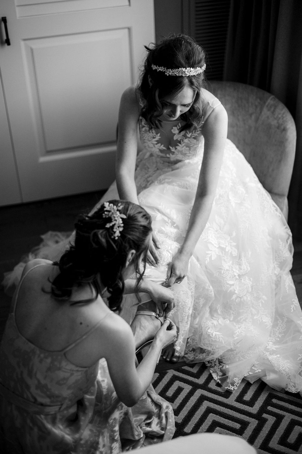 A black and white photo of a wedding dress preparation moment with delicate details.