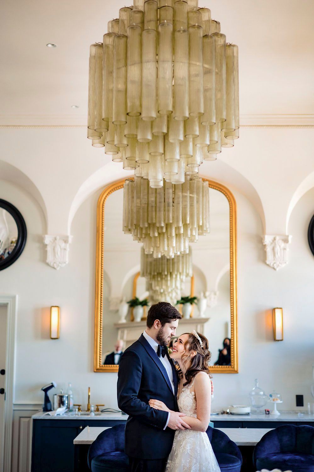 Elegant wedding venue interior with dramatic glass chandelier and arched doorways.