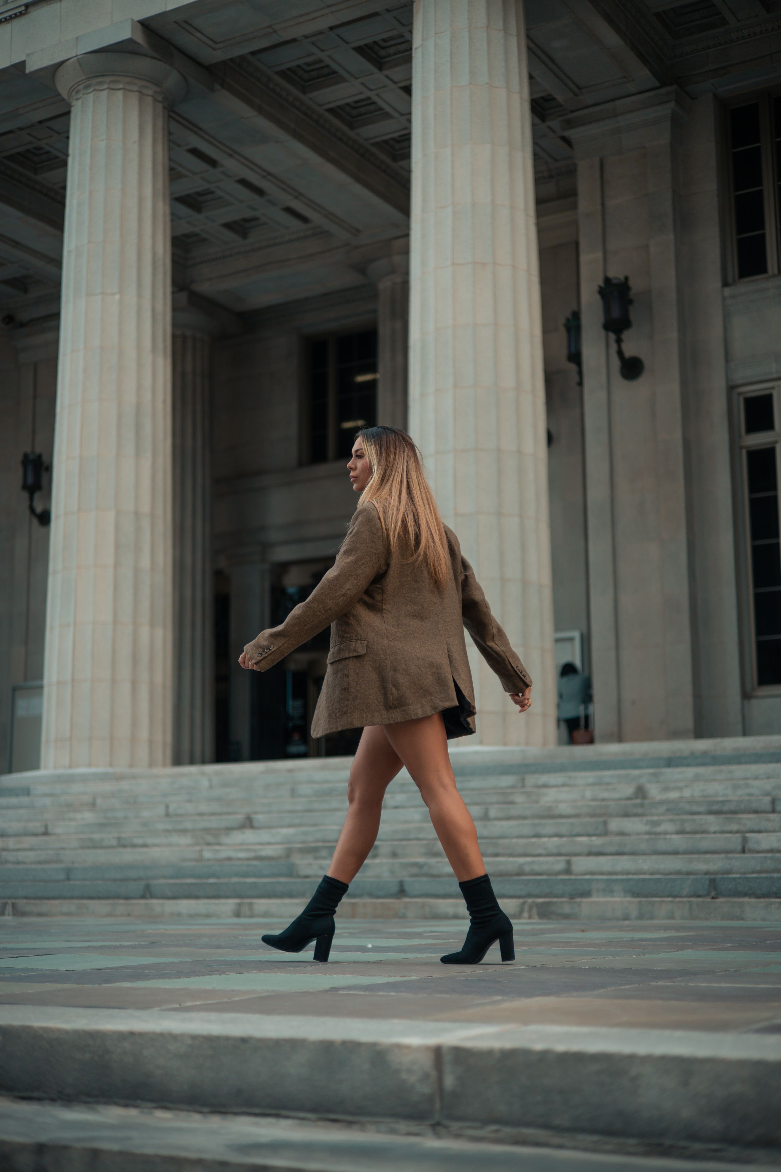 Editorial fashion portrait, woman walking across courthouse steps in Miami, cinematic South Florida style by Mannyportraits.