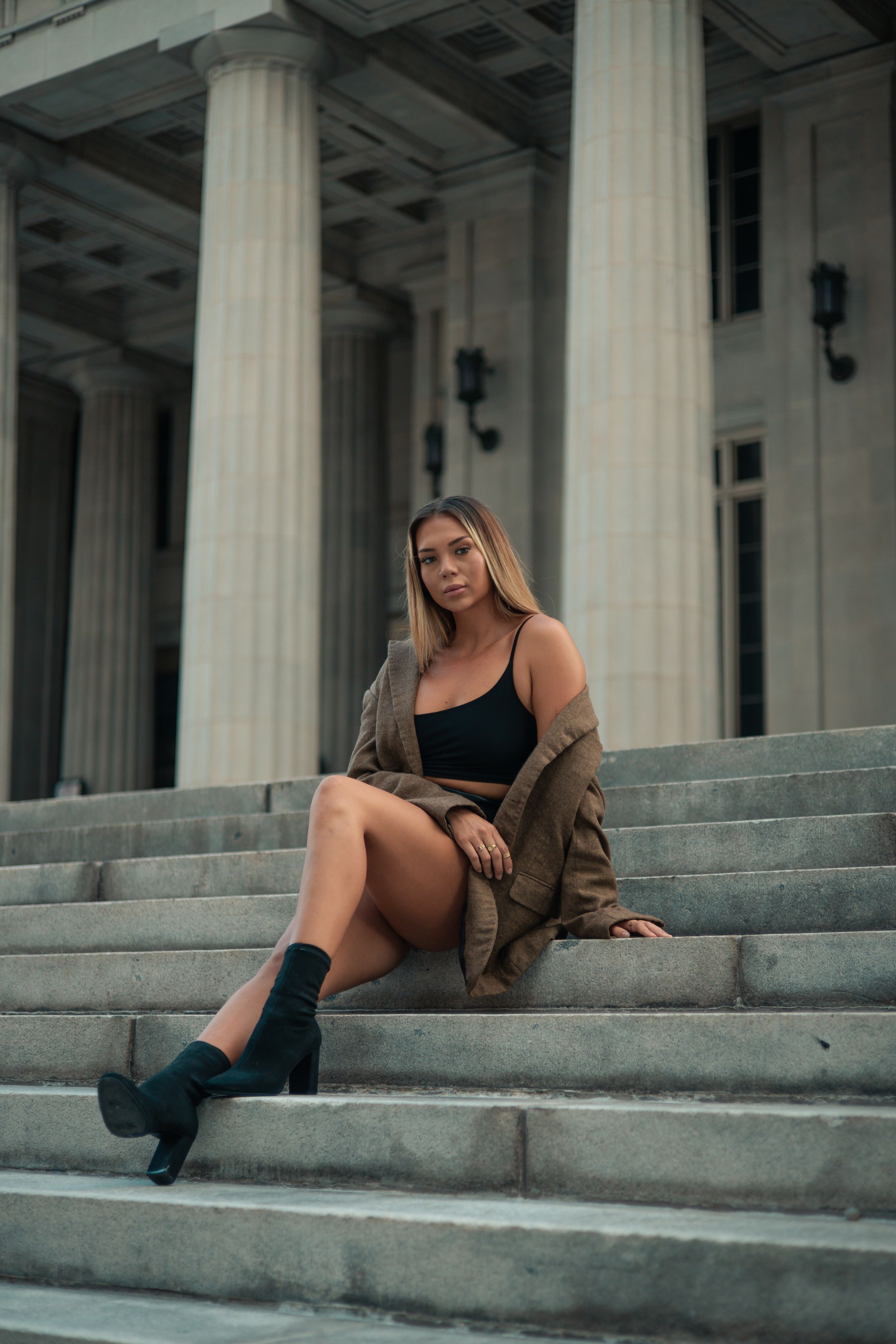 Woman in brown jacket on courthouse steps, Miami fashion editorial portrait, cinematic style by Mannyportraits South Florida.