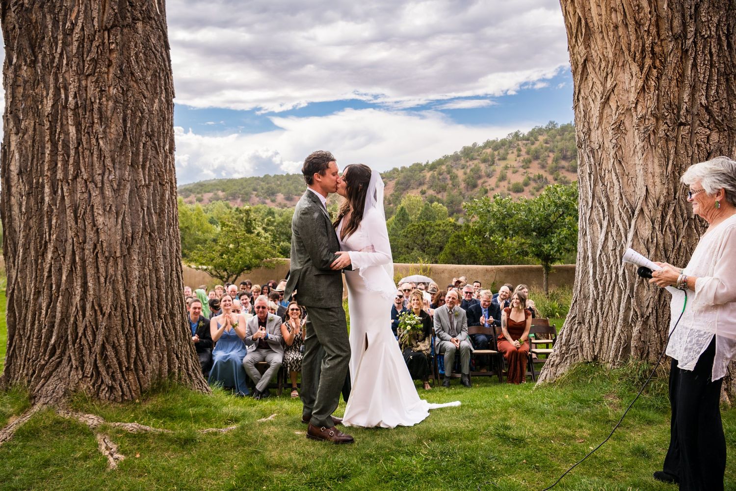 Wedding ceremony held in a picturesque grove of towering redwood trees with guests seated on wooden benches.