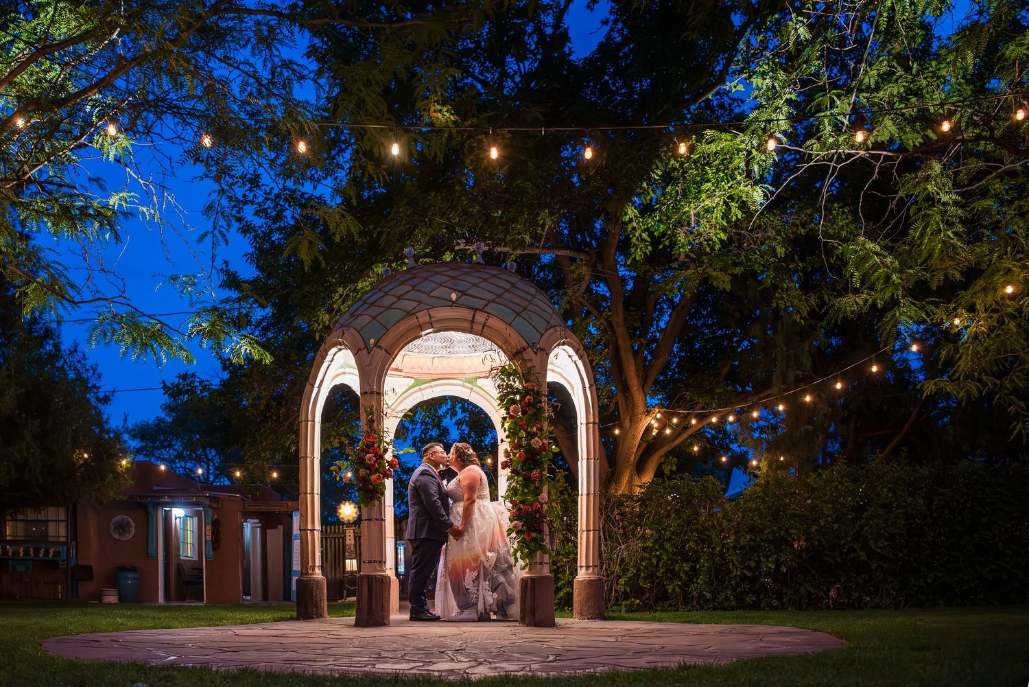 String lights illuminate an outdoor courtyard with stone archways at dusk.