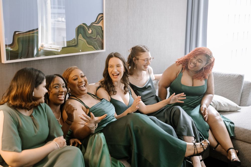 A diverse group of people sitting together on a couch laughing and having a joyful moment.