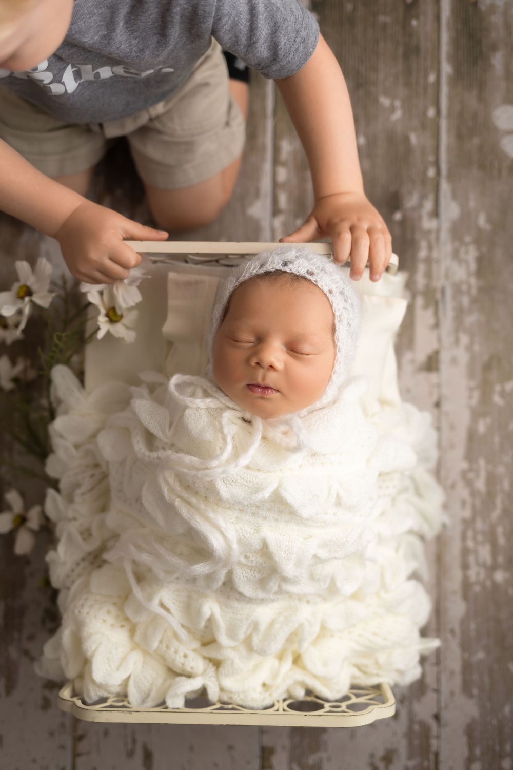 Baby girl in cream bed on wood floor, taken by Jen Knightstep, Photographer