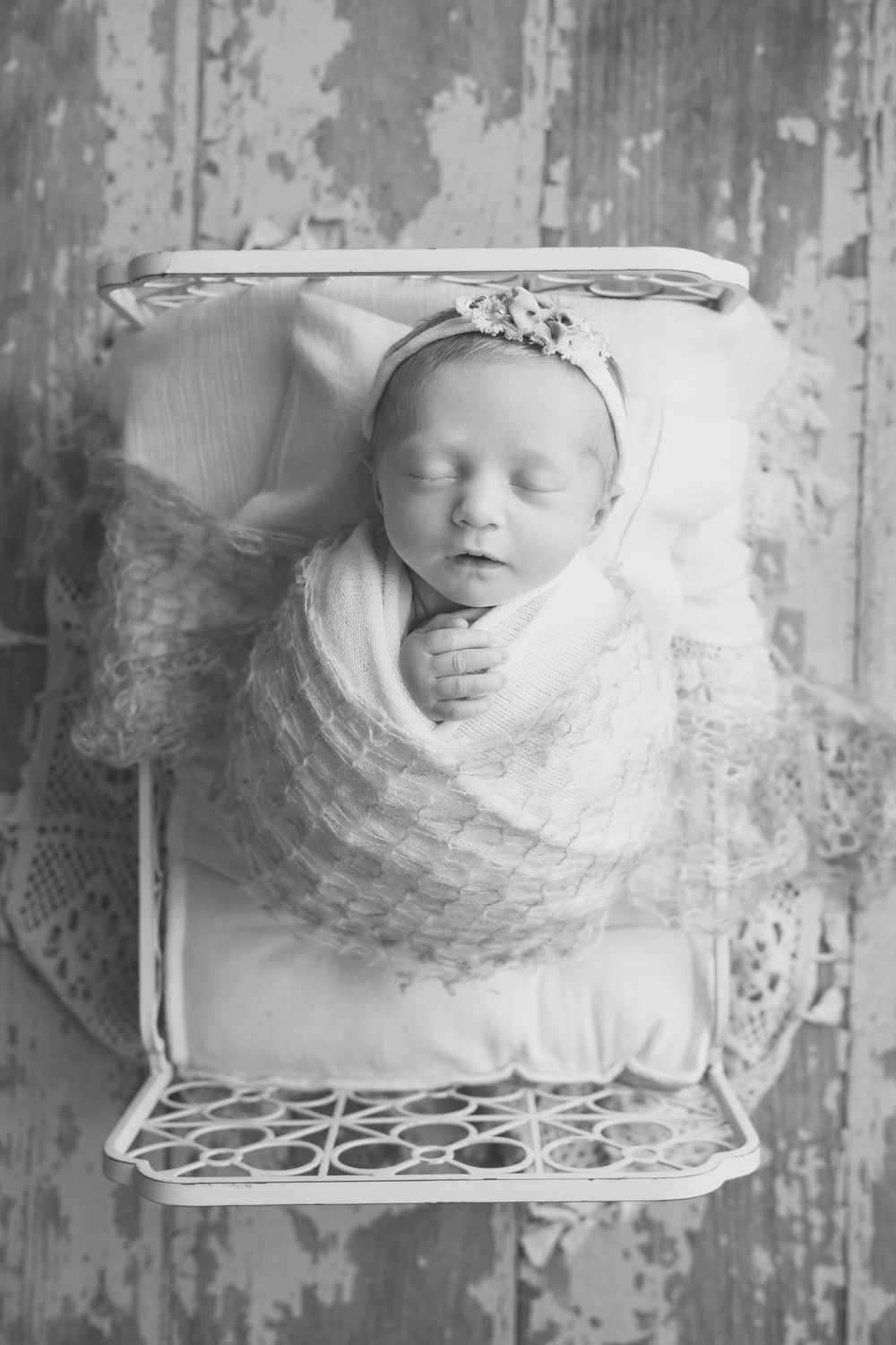 Baby girl in cream bed on wood floor, taken by Jen Knightstep, Photographer