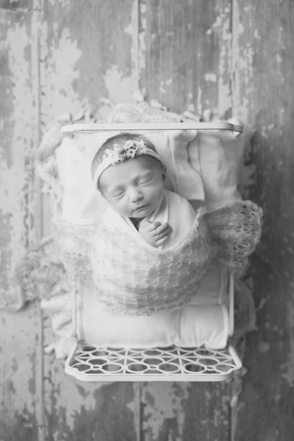 Baby girl in cream bed on wood floor, taken by Jen Knightstep, Photographer