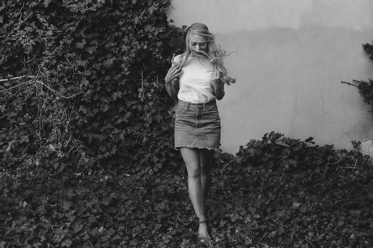 Black and white photograph of climbing figure against dark foliage background.