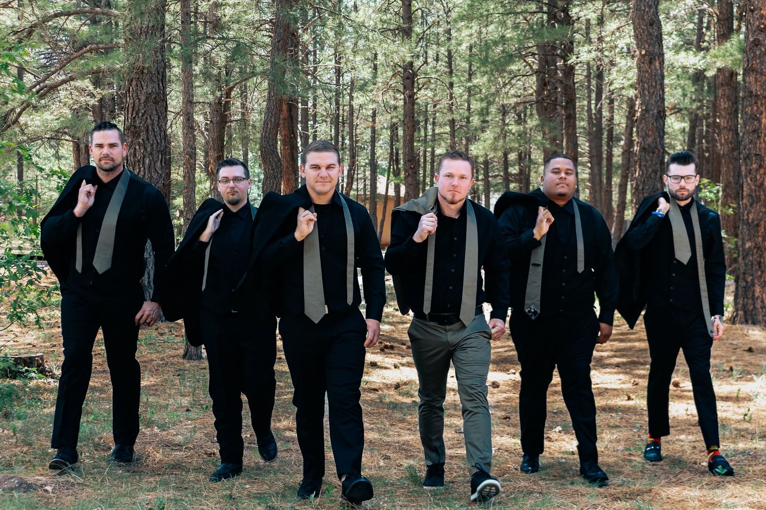 A sequence of black-suit wedding party photos taken in a rustic forest setting.
