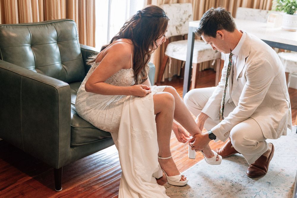 Candid Malibu wedding photography of a friend helping the bride with her heels.