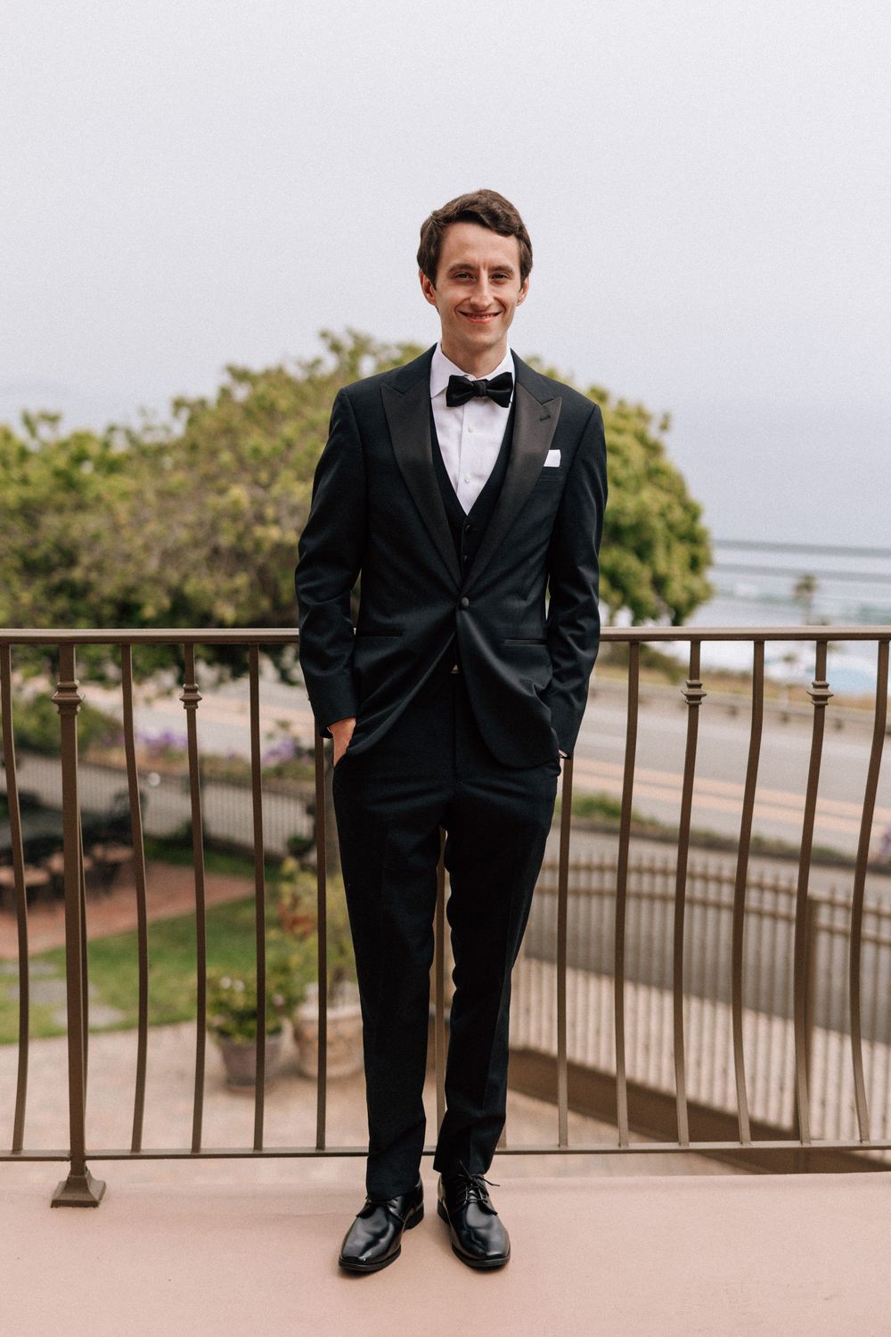 Groom standing on a balcony overlooking PCH and the Malibu ocean.