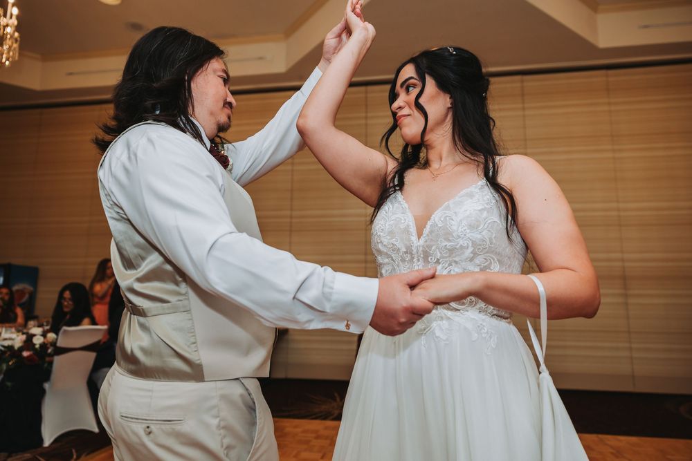 Two wedding guests twirl and dance together joyfully on the dance floor during a wedding reception celebration.