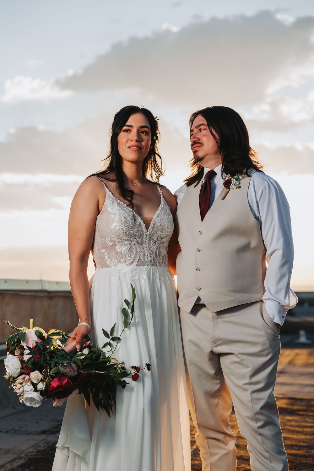 Two newlyweds sharing a romantic moment during their sunset beach wedding with lush florals and elegant attire.