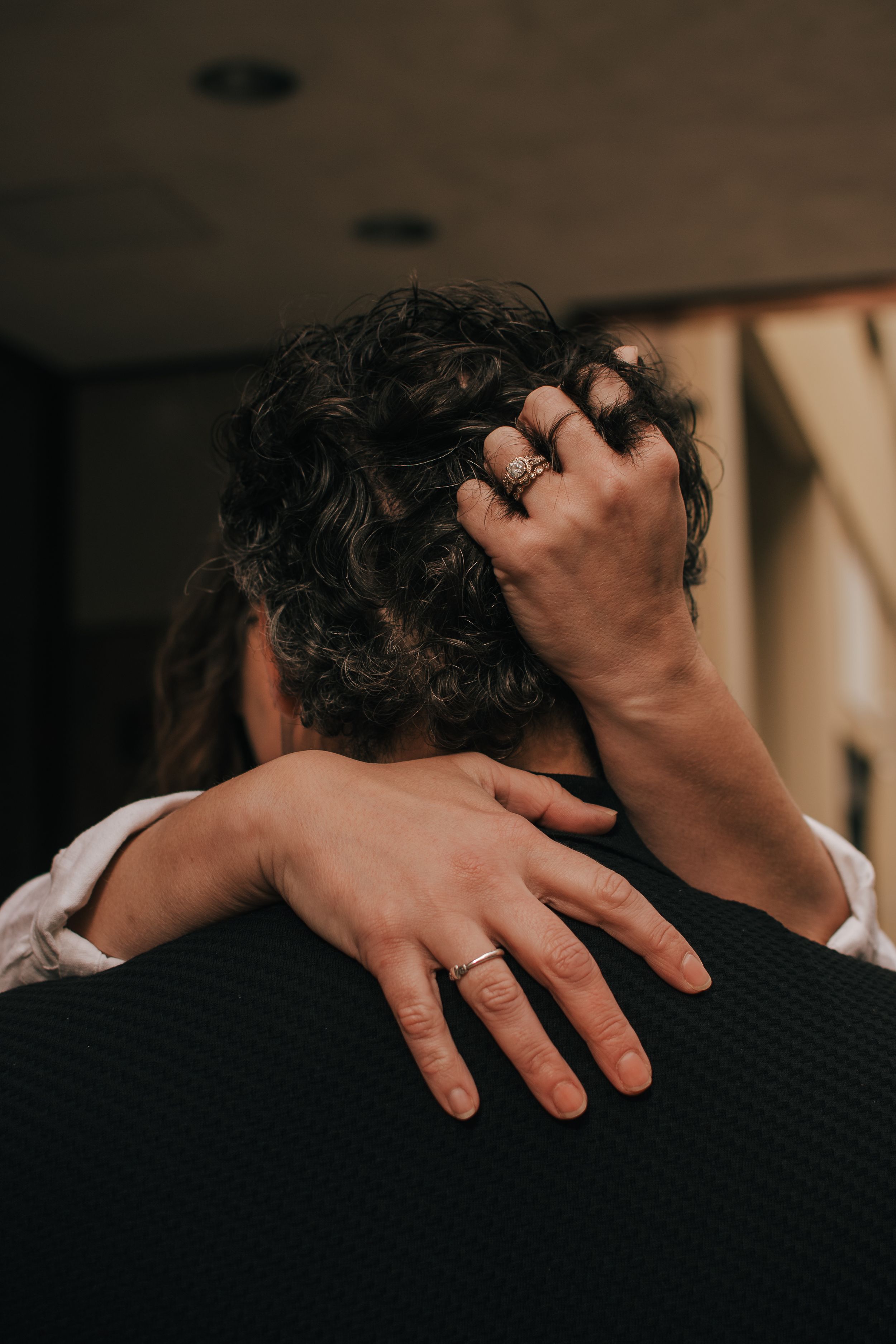 A close-up shot of hands embracing in a comforting hug against a dark background.
