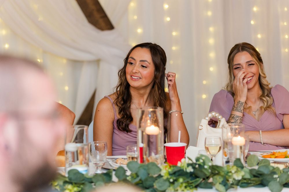 People enjoying conversation and laughter around an elegant dining table with string lights and floral centerpieces.