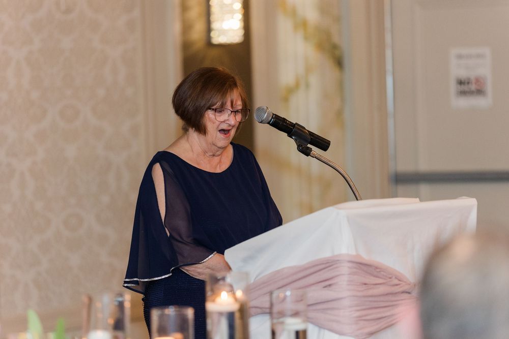 Wedding reception guests enjoy an engaging speech by a speaker at an elegant indoor venue.