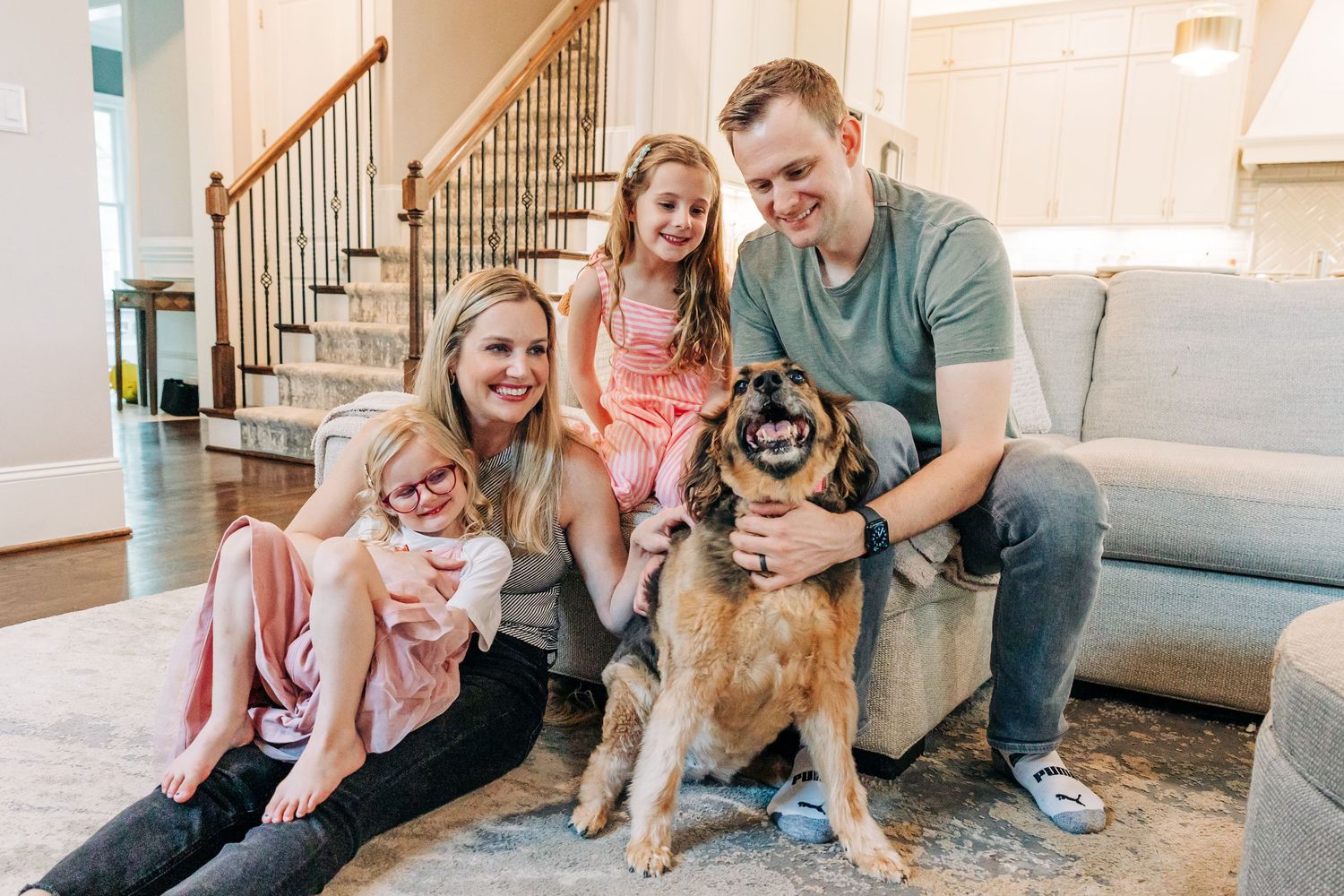 Family and dog spending quality time together while playing with toys on their living room floor in Charlotte, NC