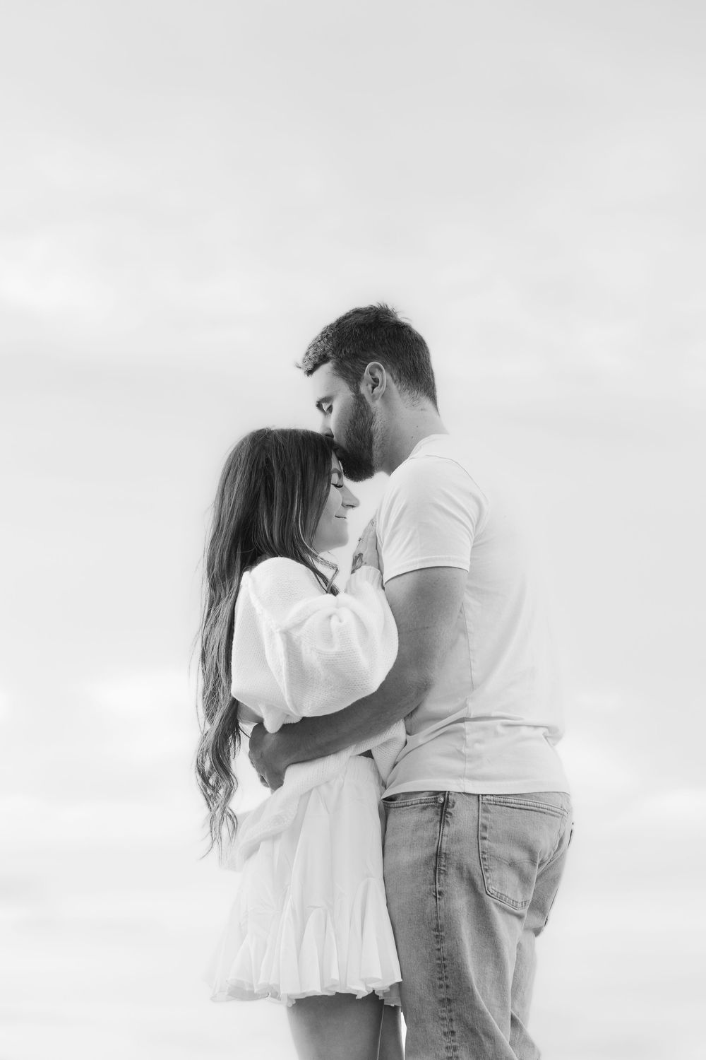 Black and white photos of a couple in white clothing sharing intimate moments against a bright background.