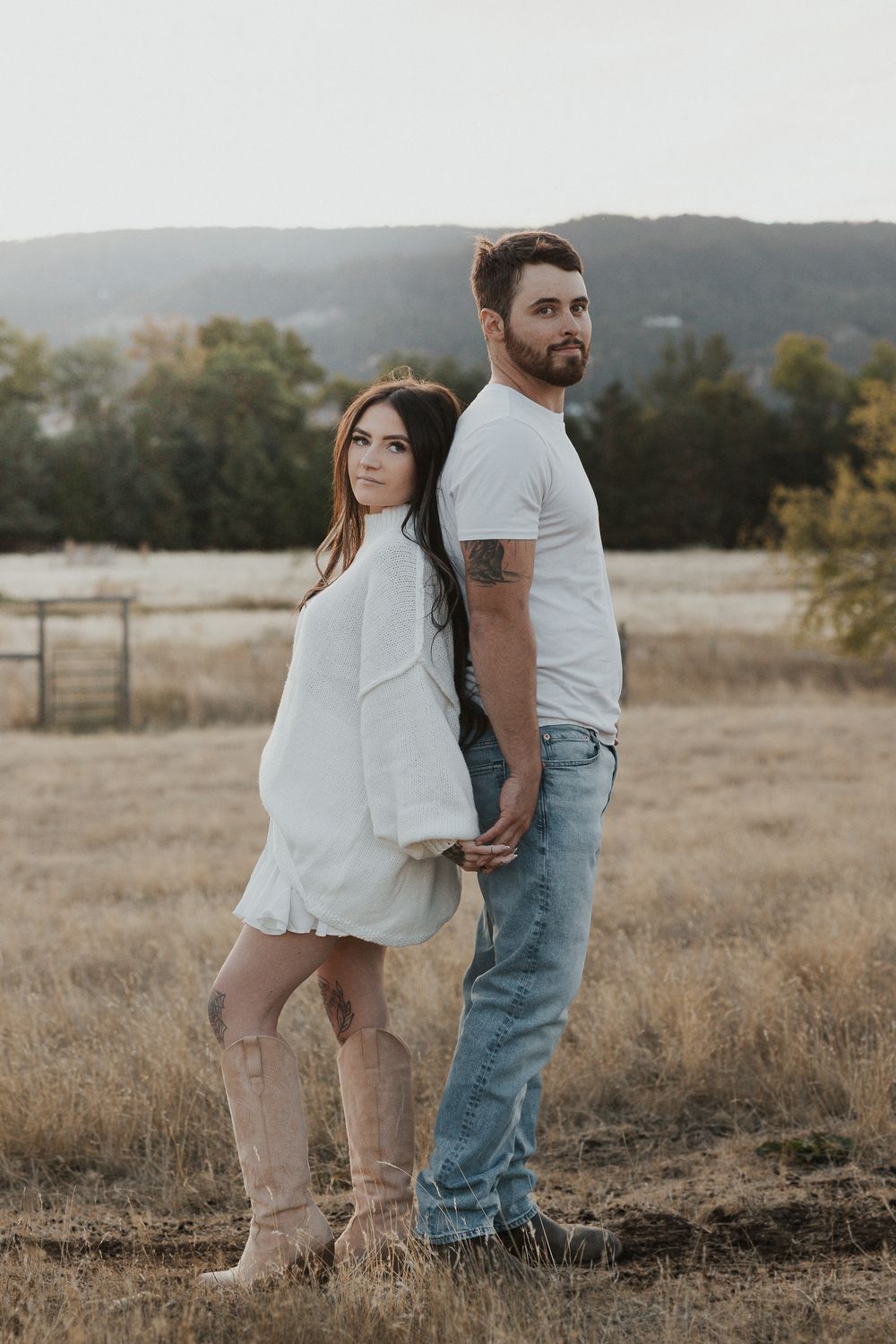 Candid shots of a couple in white and denim standing together in a rustic field setting.
