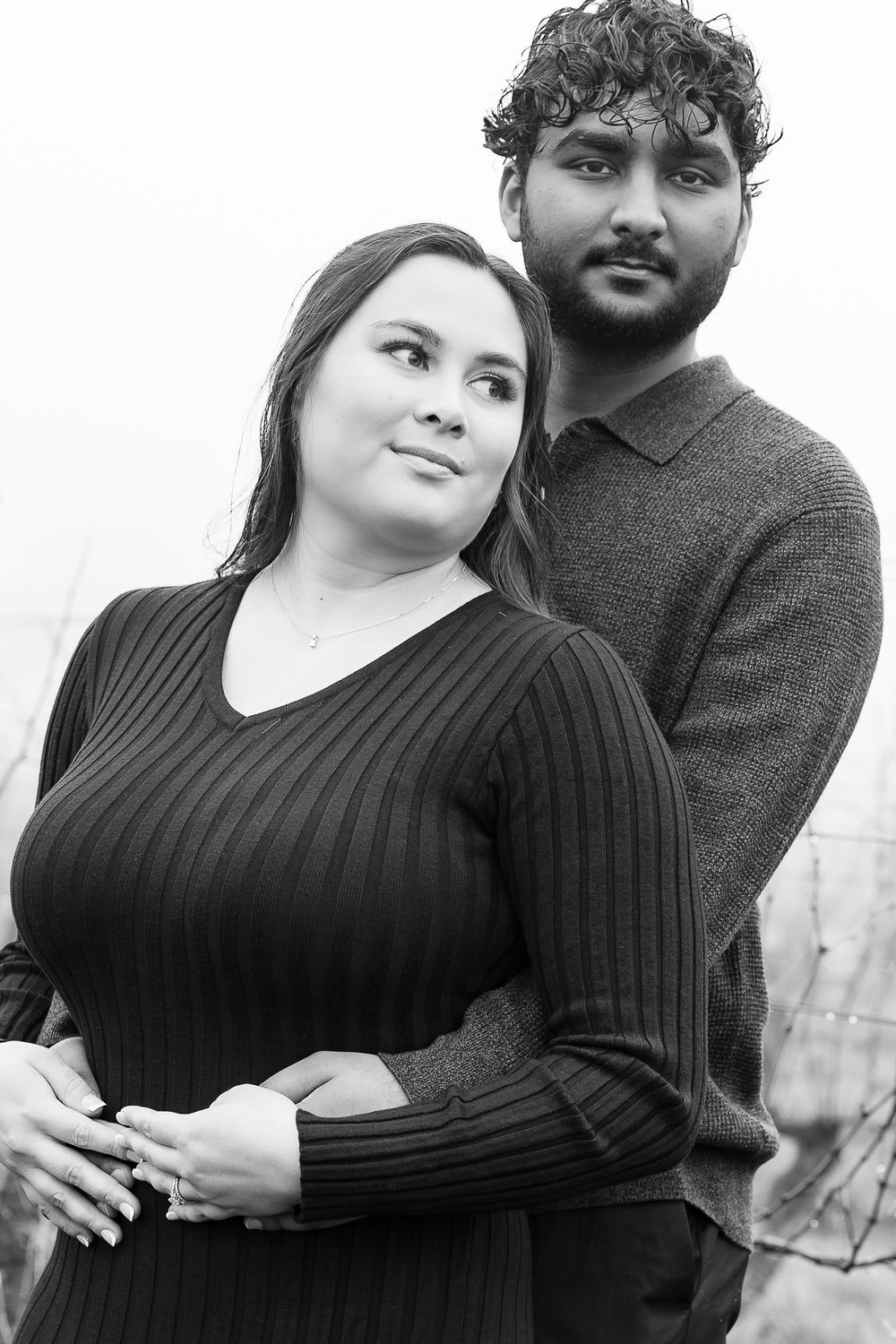 A couple in black attire poses together for romantic outdoor portraits.