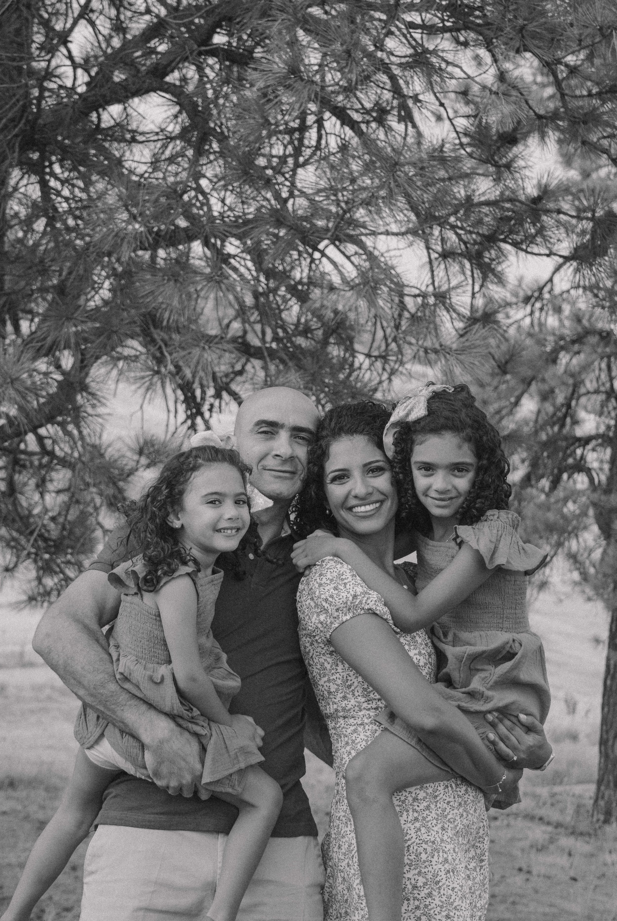 A series of black and white vintage style photos showing a family group playfully posing together under a tree.
