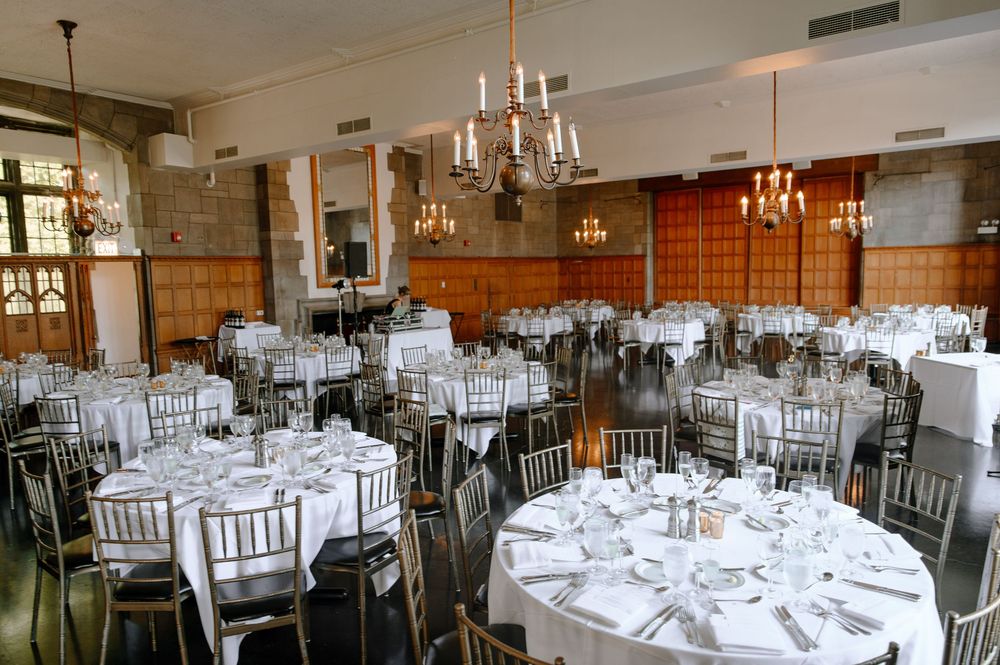 Elegant wedding reception venue with round tables, white linens, crystal chandeliers and silver chiavari chairs.