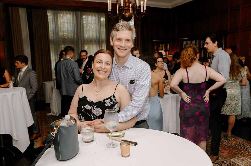 Wedding guests celebrate at an elegant indoor reception with candlelit tables and stone walls.