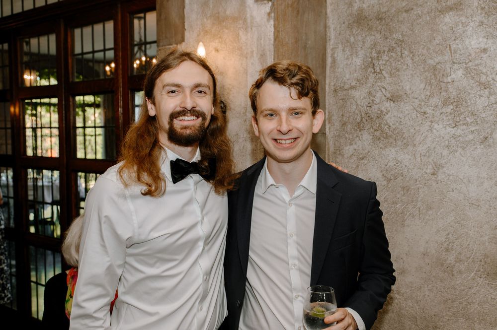 Two guests in formal attire share a candid moment at an elegant indoor reception venue.