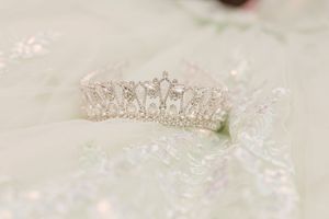 Delicate crystal bridal tiaras with rhinestones arranged on a light neutral surface with sparkly reflections.