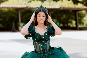 Elegant emerald formal dress with off-shoulder design and crystal embellishments photographed in natural light.