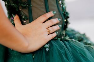 Close-up details of an emerald green ball gown showing intricate beadwork and voluminous tulle layers.