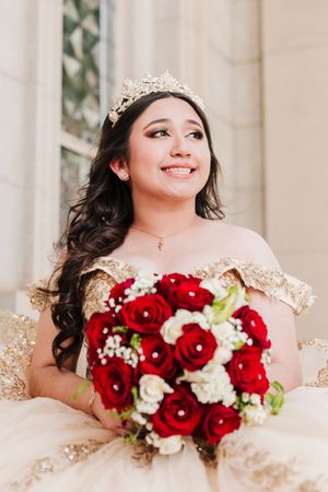 A classic bridal bouquet features deep red roses and white baby's breath against an elegant cream-colored dress.
