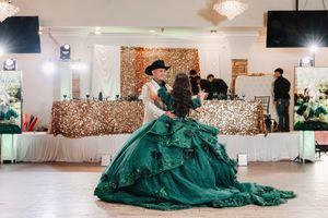 Elegant quinceañera celebration features a stunning emerald green ball gown against a backdrop of gold sequin decor.
