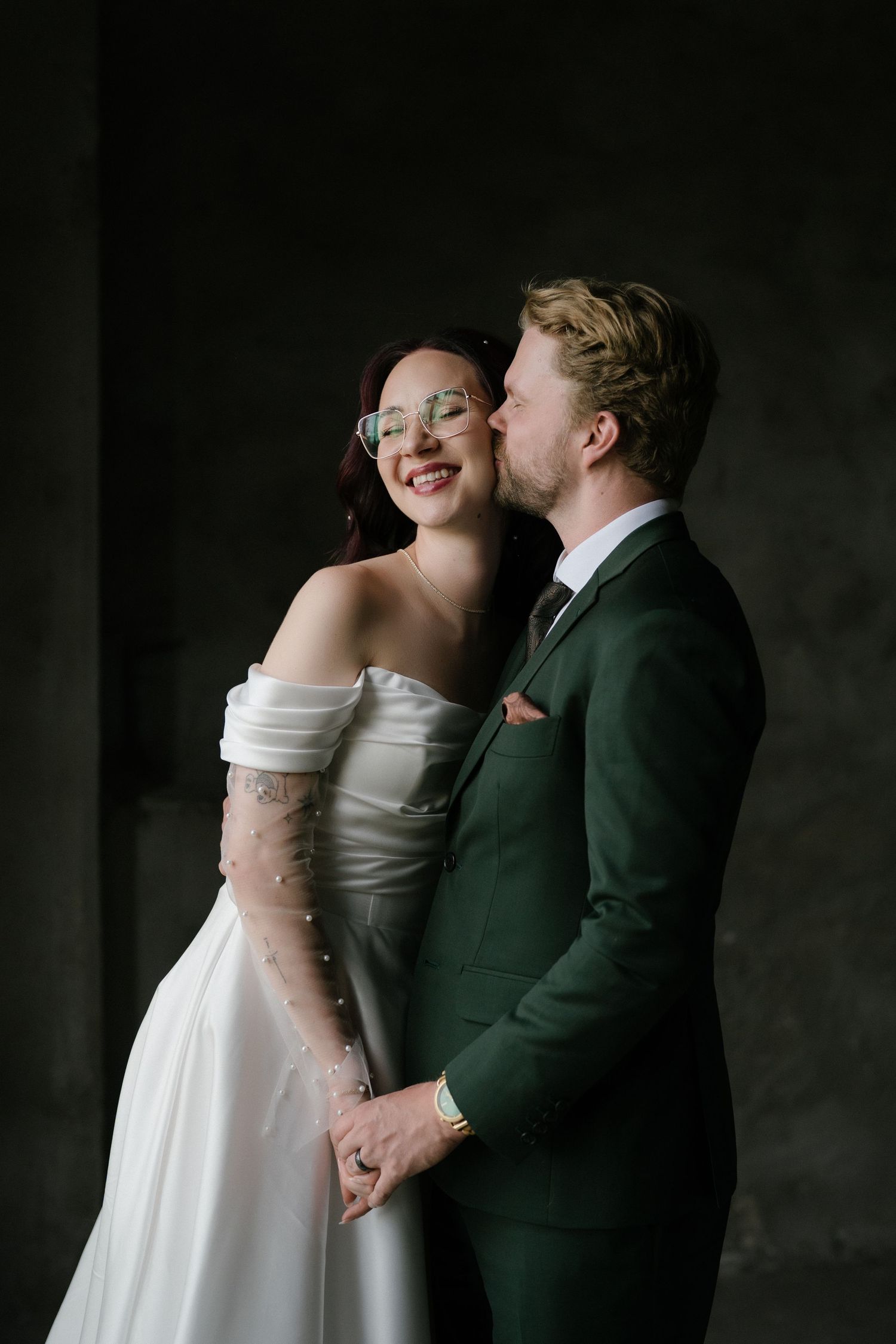 Romantic moment between newlyweds in elegant wedding attire with bride in white dress and groom in dark suit.