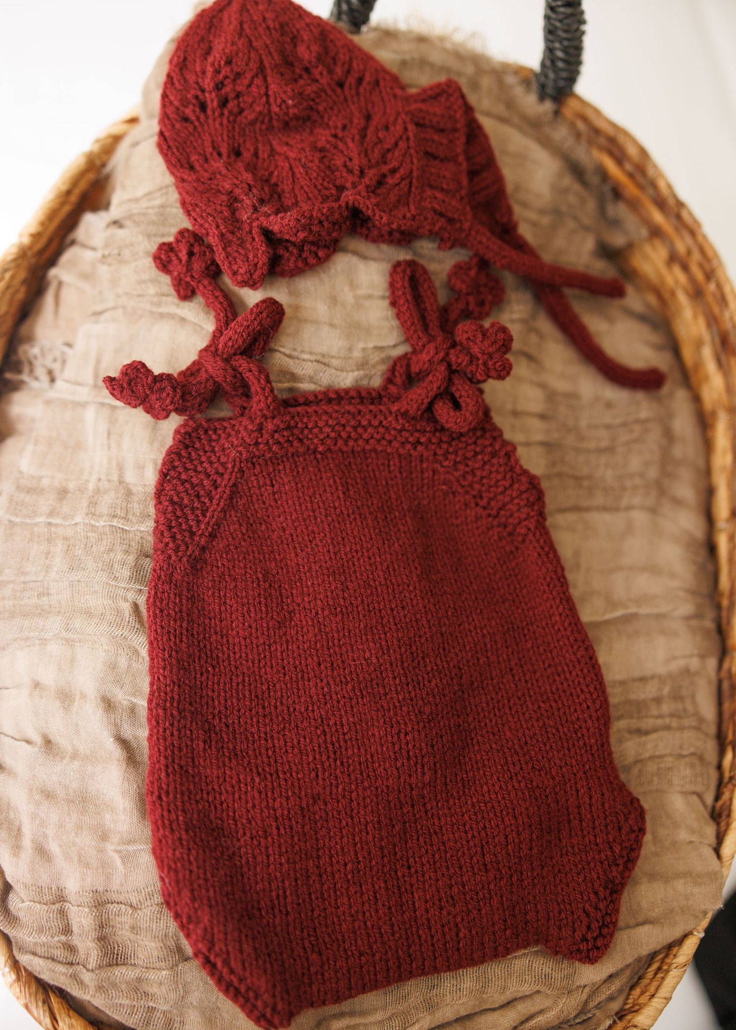 Rustic brown linen baby romper with delicate white lace trim and crochet details displayed on vintage lace background.