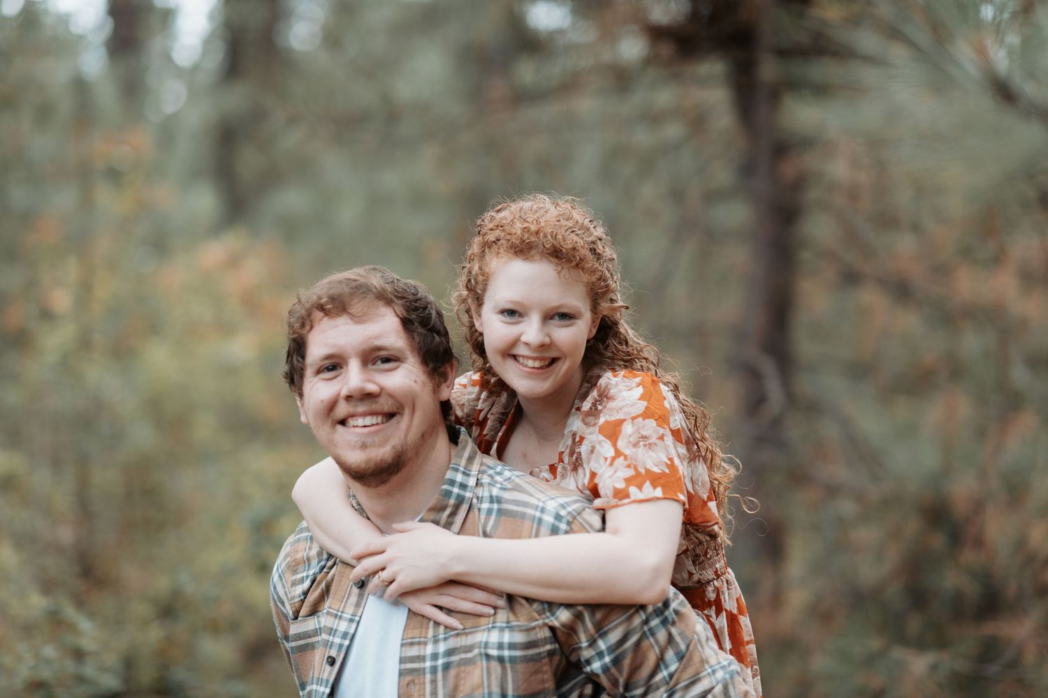 Young man giving his fiance a piggy back ride during their playful engagement session in North Idaho. Taken at Kiwanis Park.