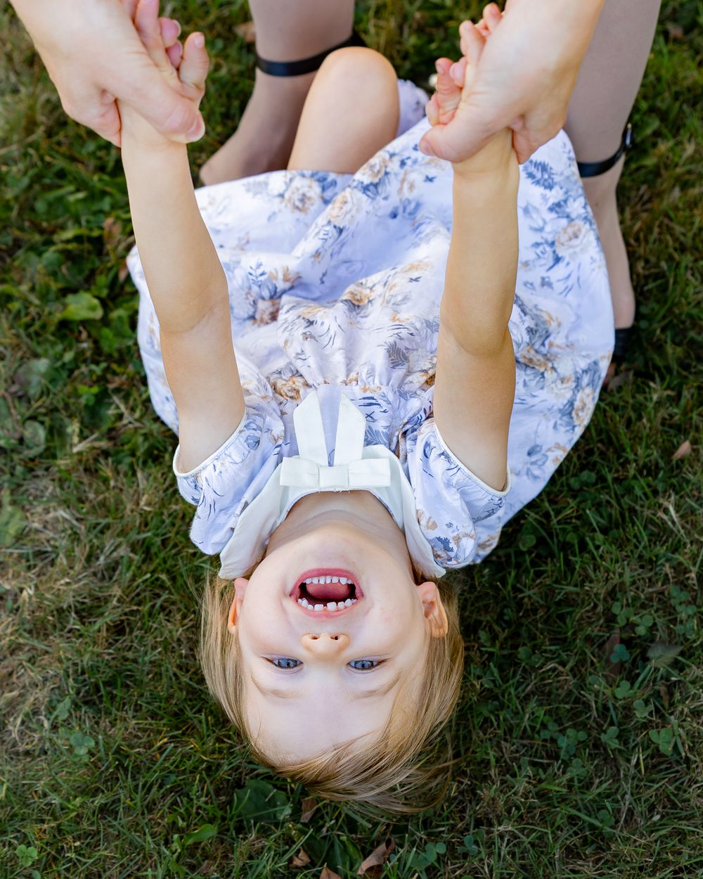 A girl candidly laughs in a grassy field during family photos at Acton Arboretum in Acton, MA with Lisa West Photography.