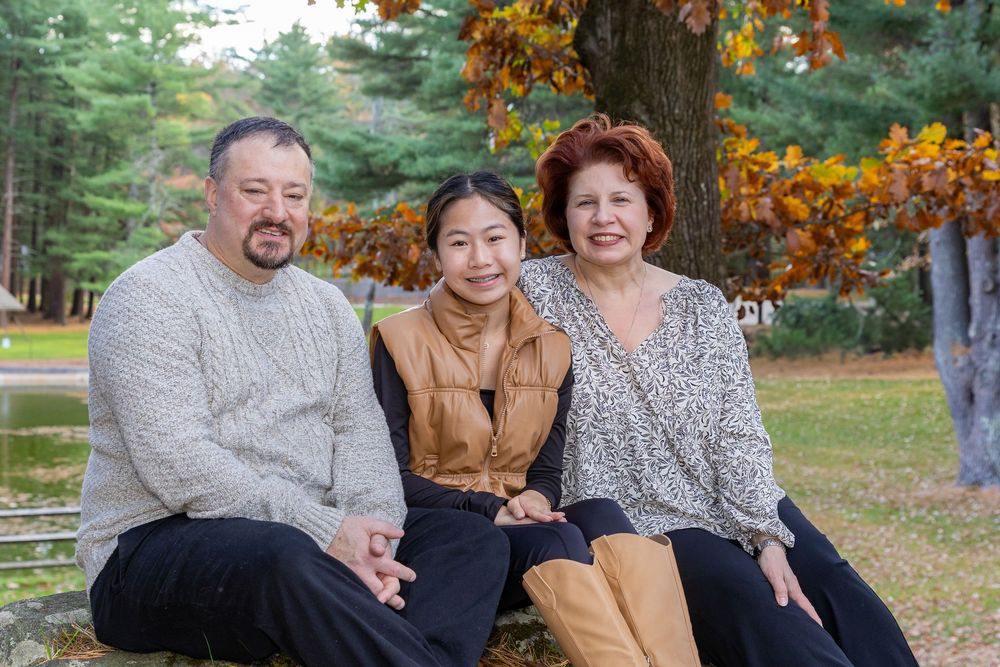 A family pose for a fall portrait with bright leaves during family photo session at Camp Sewataro in Sudbury, MA with Lisa West Photography.