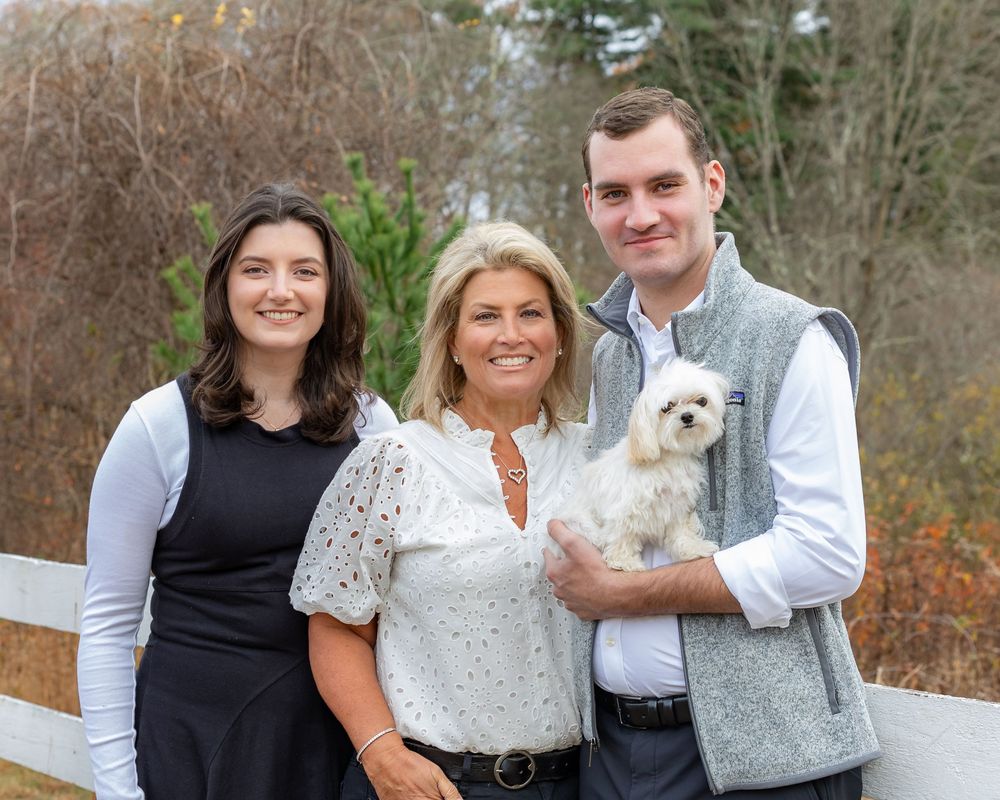 A family poses for a fall portrait with their dog during family photo session at Wolbach Farm in Sudbury, MA with Lisa West Photography.