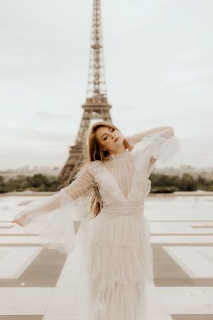 Flowing white dress twirls gracefully against the backdrop of the Eiffel Tower in Paris.