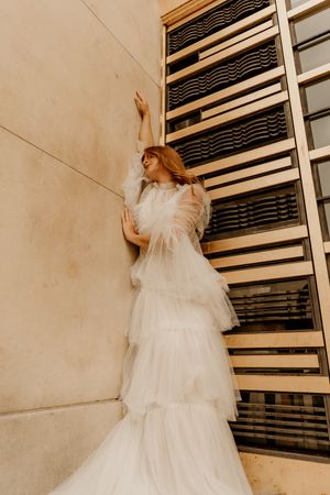 A bride in a flowing white tulle gown poses in front of a rustic wall in a creative multi-panel photo sequence.