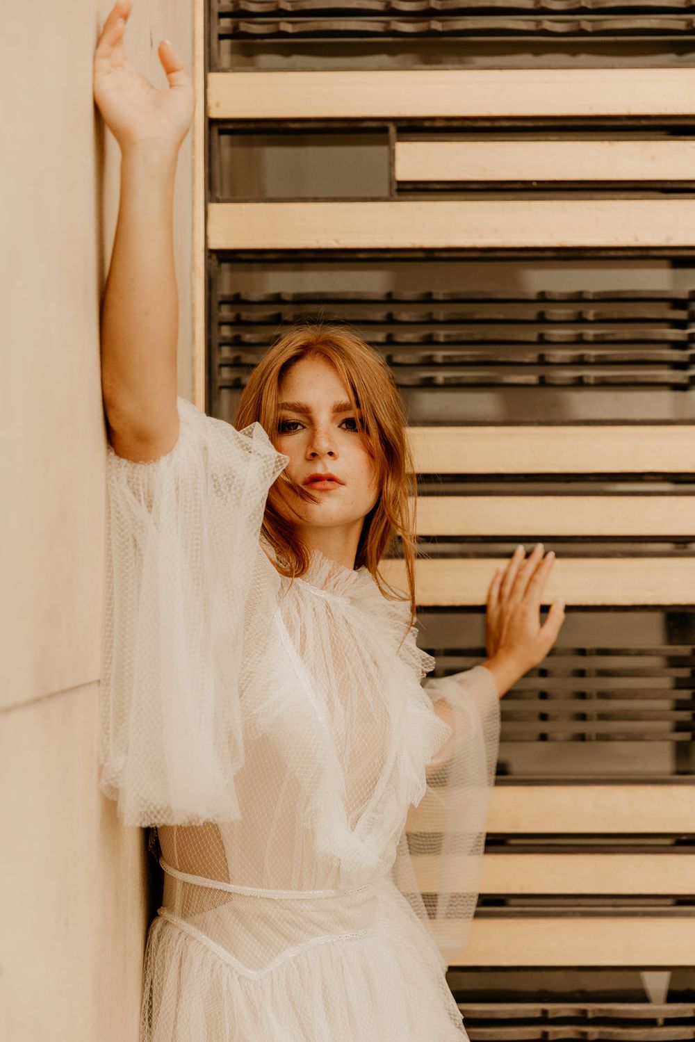 Five artistic portrait photos showing ethereal movement in a white flowing dress against industrial window blinds background.