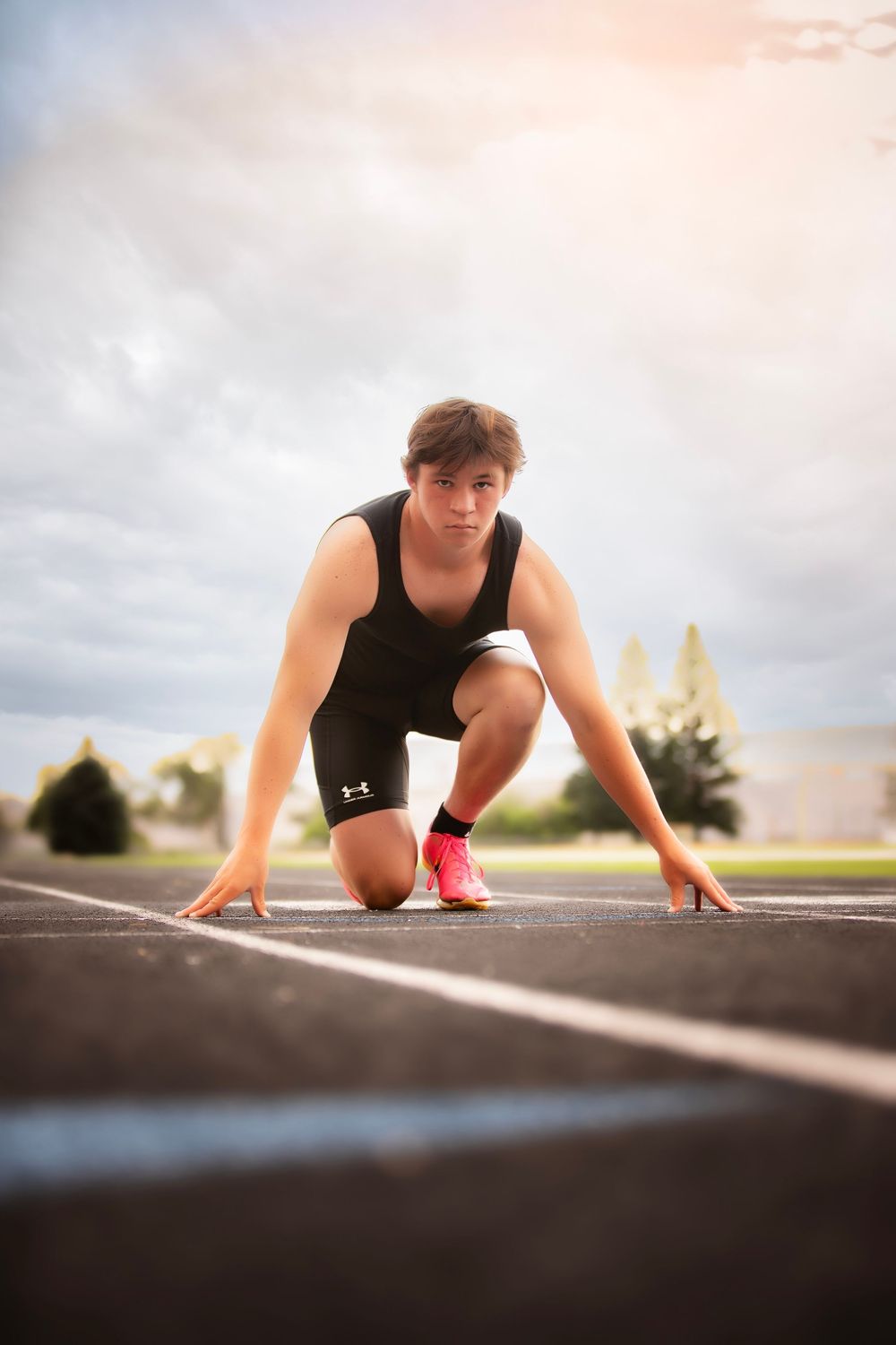 Person in black athletic wear performs crawling exercises on an outdoor track during an intense workout session.