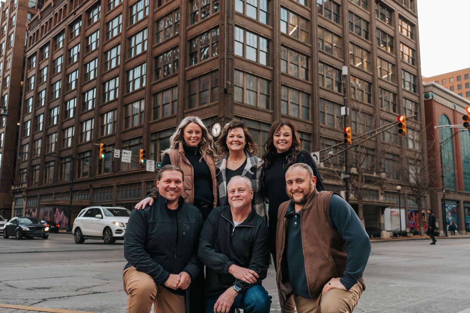 Group portrait in front of historic brick building in urban setting.