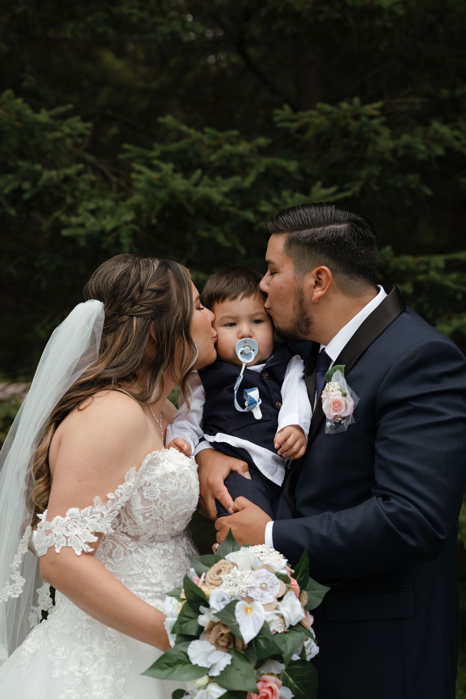 An intimate wedding scene in a forest setting with the bride holding a beautiful floral bouquet.