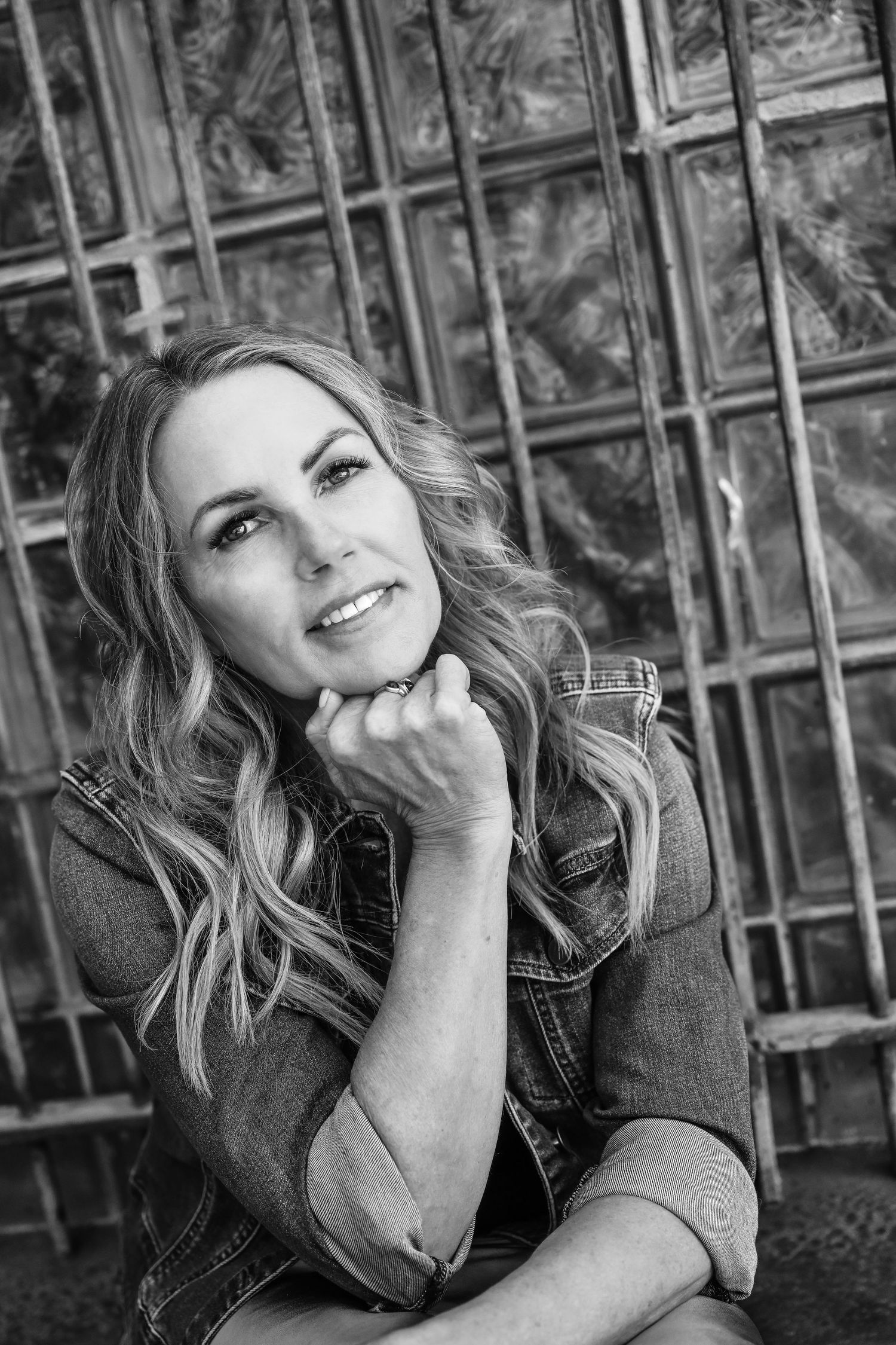 Black and white portrait against textured wall backdrop with dramatic lighting.