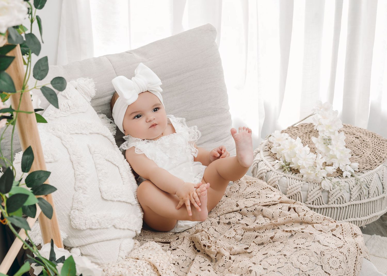 Newborn photography with purple knit accessories and delicate flowers arranged in a rustic basket.