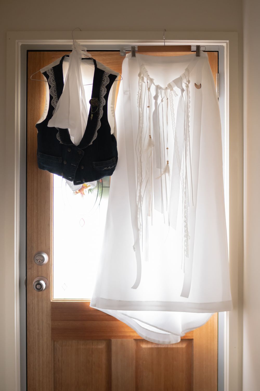 Several white and black garments hanging on a wall-mounted clothing rod against plain white walls.