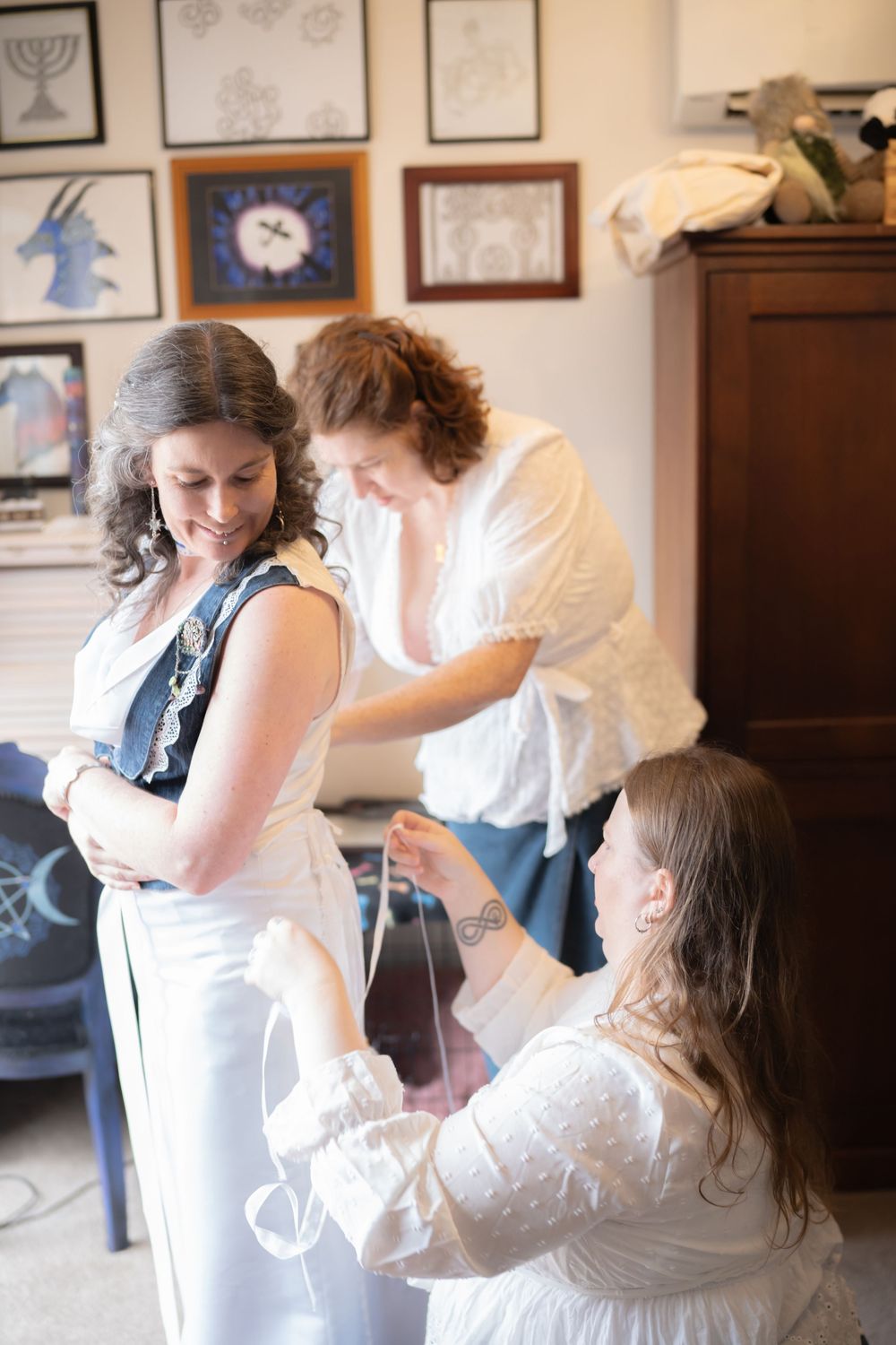 A bridal preparation scene in a room decorated with art on the walls showing candid getting ready moments.